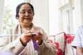 Senior woman wearing eyeglasses knitting in nursing home
