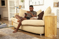 Teenage boy sitting on sofa and using phone