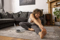 Smiling woman stretching in living room in front of laptop