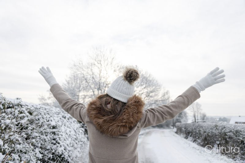 Rear view of woman with arms raised in winter landscape