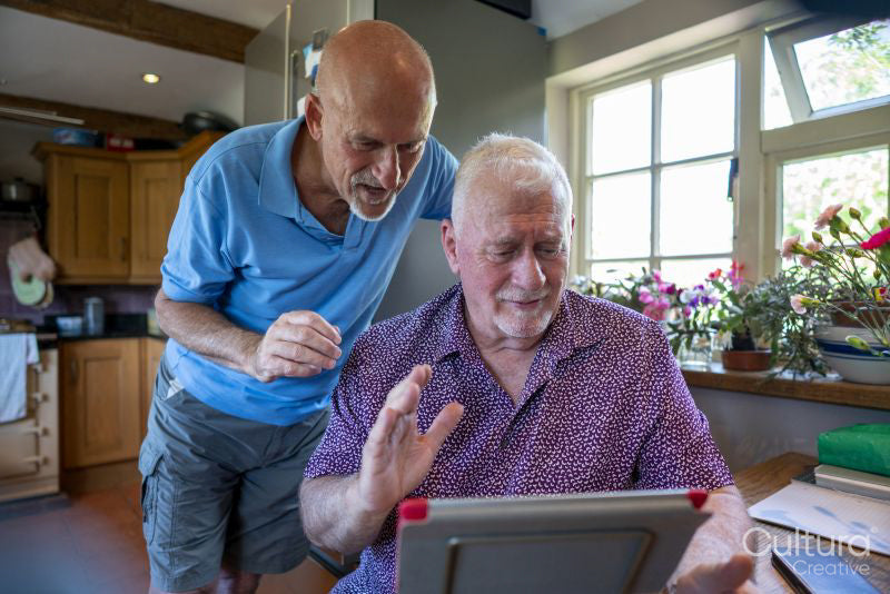 Senior male couple having video call on tablet