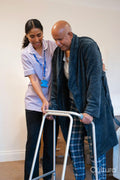 Nurse helping senior man to walk with mobility walker at nursing home