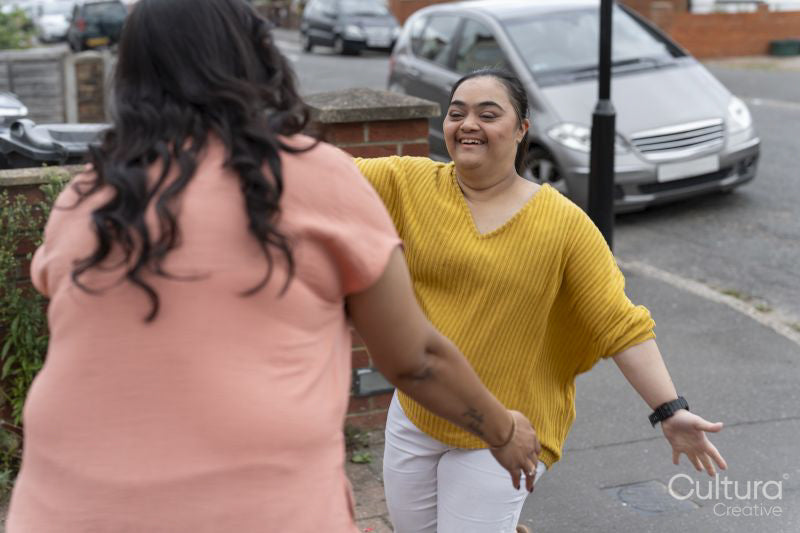 Down syndrome daughter embracing mother on sidewalk