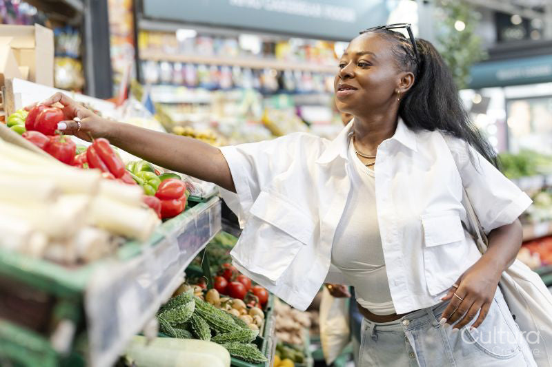 Young woman choosing fresh vegetables in grocery store
