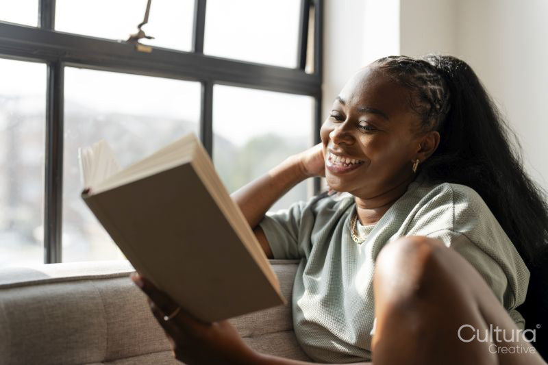 Young woman reading book while resting at home
