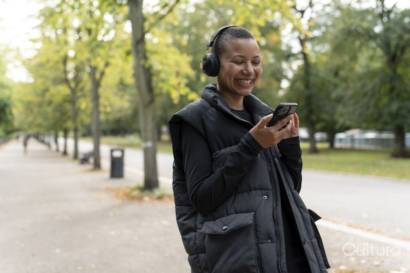 Smiling woman with headphones and smart phone in park