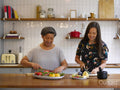 Mother and adult daughter cutting vegetables in kitchen