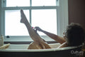 Woman shaving leg in bathtub