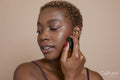 Studio portrait of woman applying serum on face
