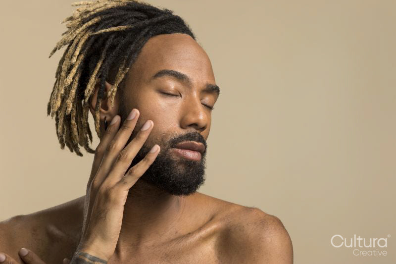 Studio shot of young man with dreadlocks with closed eyes