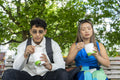 Tourist couple sitting on park bench eating street food