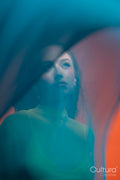 Woman in a yellow dress veiled by blue sheer fabric