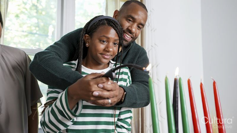 Family with daughter lighting kinara candles