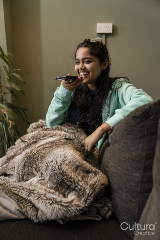 Young woman sitting on sofa and using phone