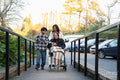 Family during walk outside nursing home with senior lady sitting in wheelchair