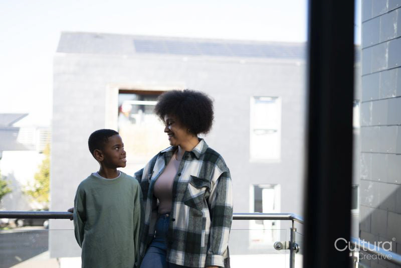 Smiling mother and son standing on balcony
