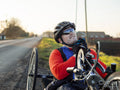Disabled man on handcycle fastening cycling helmet on roadside