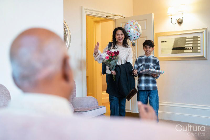 Mature woman and boy arriving for birthday visit with senior man in nursing home