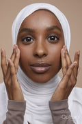 Studio portrait of young woman in white hijab touching face