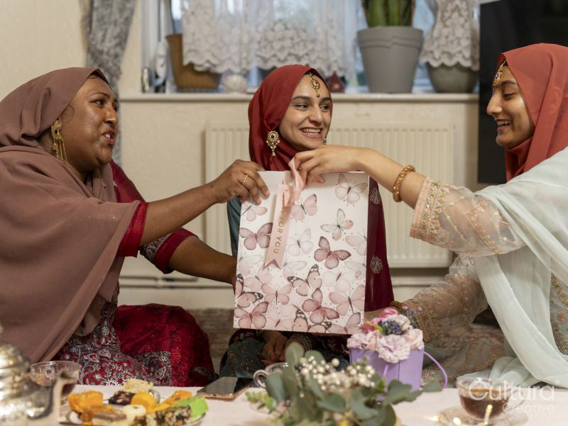 Smiling women sharing gifts during Ramadan celebration at home