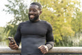 Smiling athletic man looking at smart phone on footbridge in park