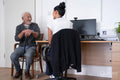 Smiling senior patient talking to female doctor at desk in office