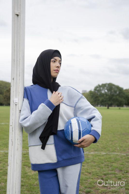 Portrait of woman in hijab standing in soccer field with soccer ball