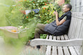 Smiling woman with smart phone in vegetable garden