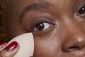 Close-up of woman applying make up foundation with sponge
