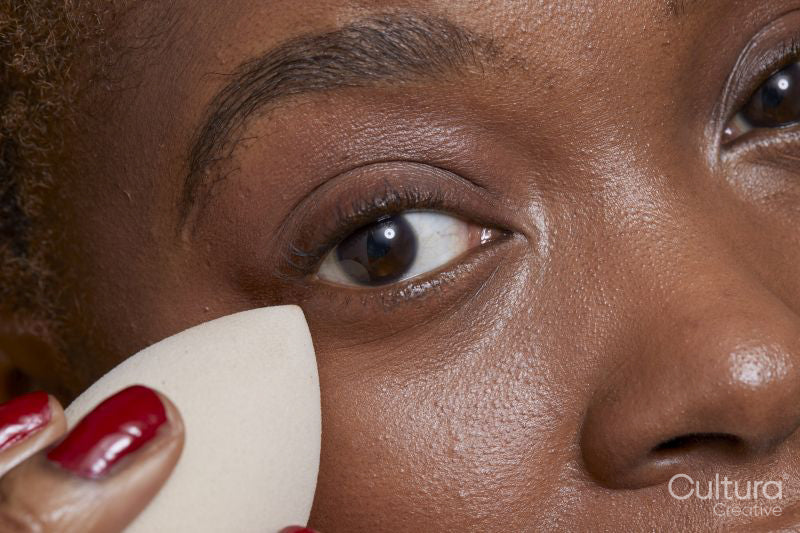 Close-up of woman applying make up foundation with sponge