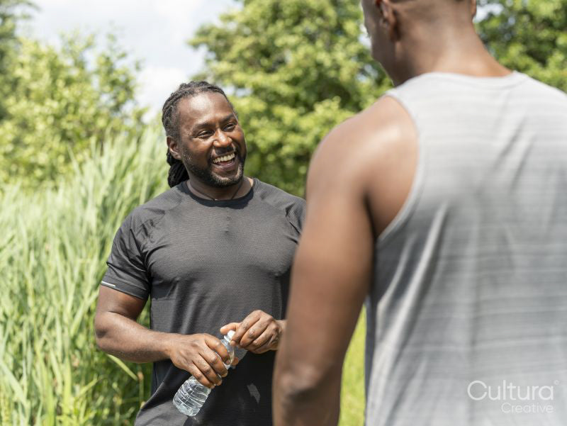 Two men drinking water after exercising outdoors