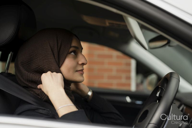 Young woman wearing hijab driving car