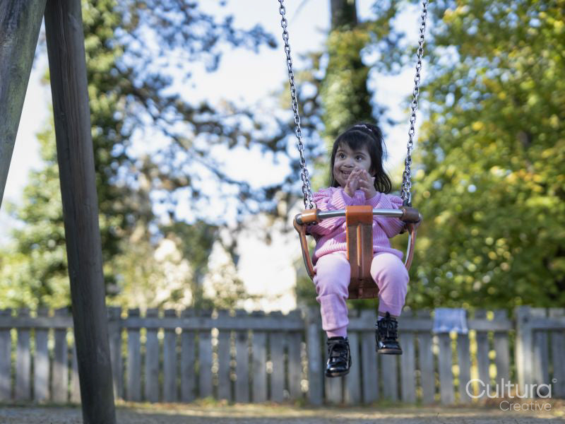 Girl with Down syndrome swinging on swing on playground