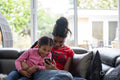 Two girls sitting on sofa looking at smartphone