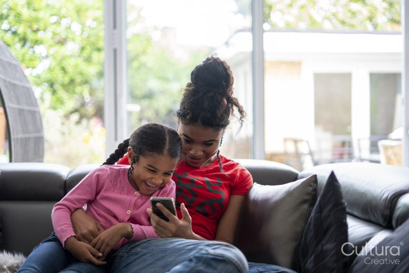 Two girls sitting on sofa looking at smartphone