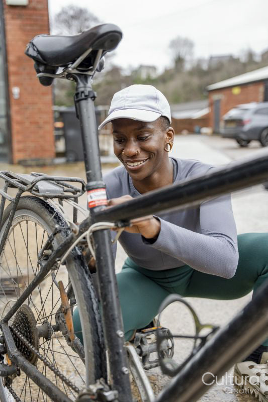 Smiling woman adjusting bicycle wheel