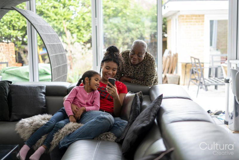 Two girls and woman looking at smartphone in living room