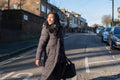 Portrait of smiling woman in long overcoat crossing street
