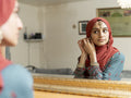 Woman looking at mirror and putting on earrings