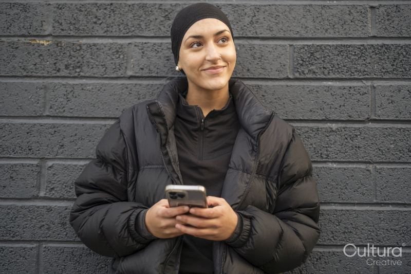 Young woman leaning on wall and using smartphone