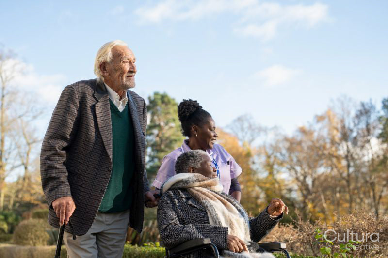 Senior people accompanied by nurse going on walk in park