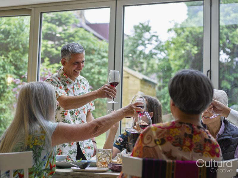Family toasting with red wine at dinner table