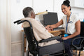 Smiling female doctor talking to senior woman sitting in wheelchair