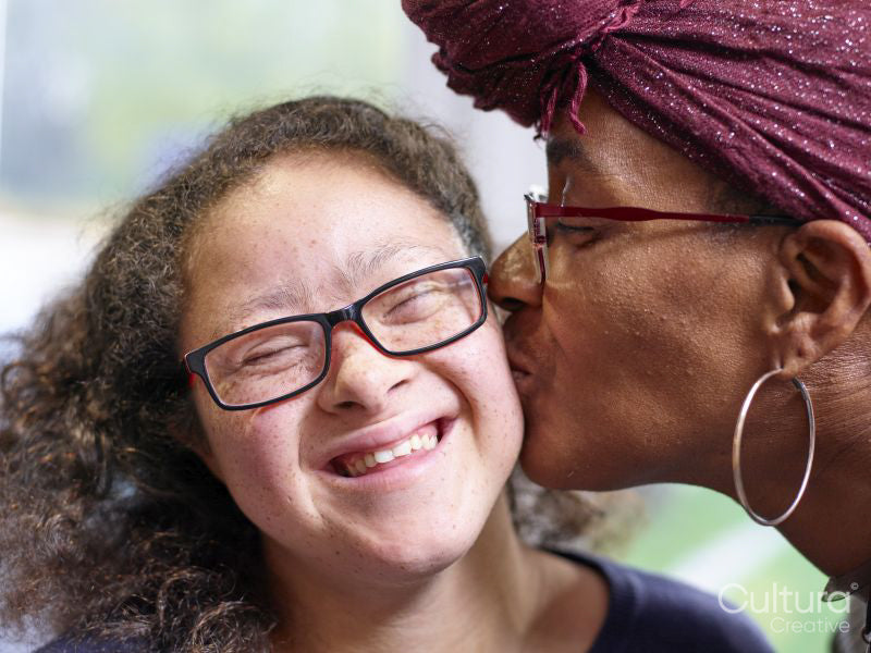 Mother kissing daughter with Down syndrome