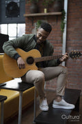 Young man playing acoustic guitar in office lounge