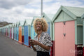 Smiling woman using smart phone near beach huts