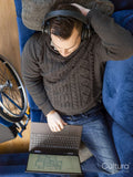 Overhead view of man with headphones and laptop on sofa next to wheelchair