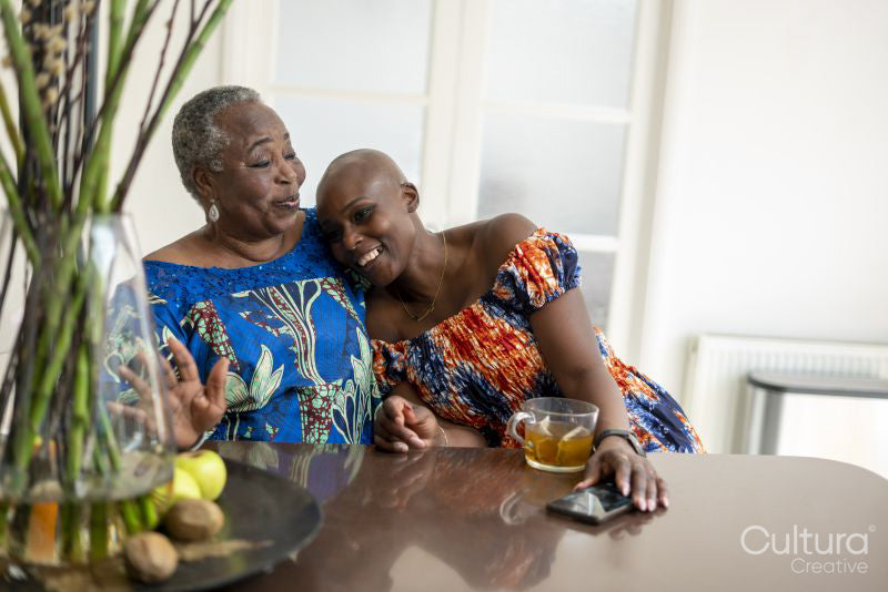 Smiling senior woman embracing adult daughter at table