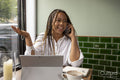 Smiling woman with laptop and smart phone at cafe table