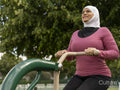 Sutton,Smiling woman in headscarf exercising at park gym